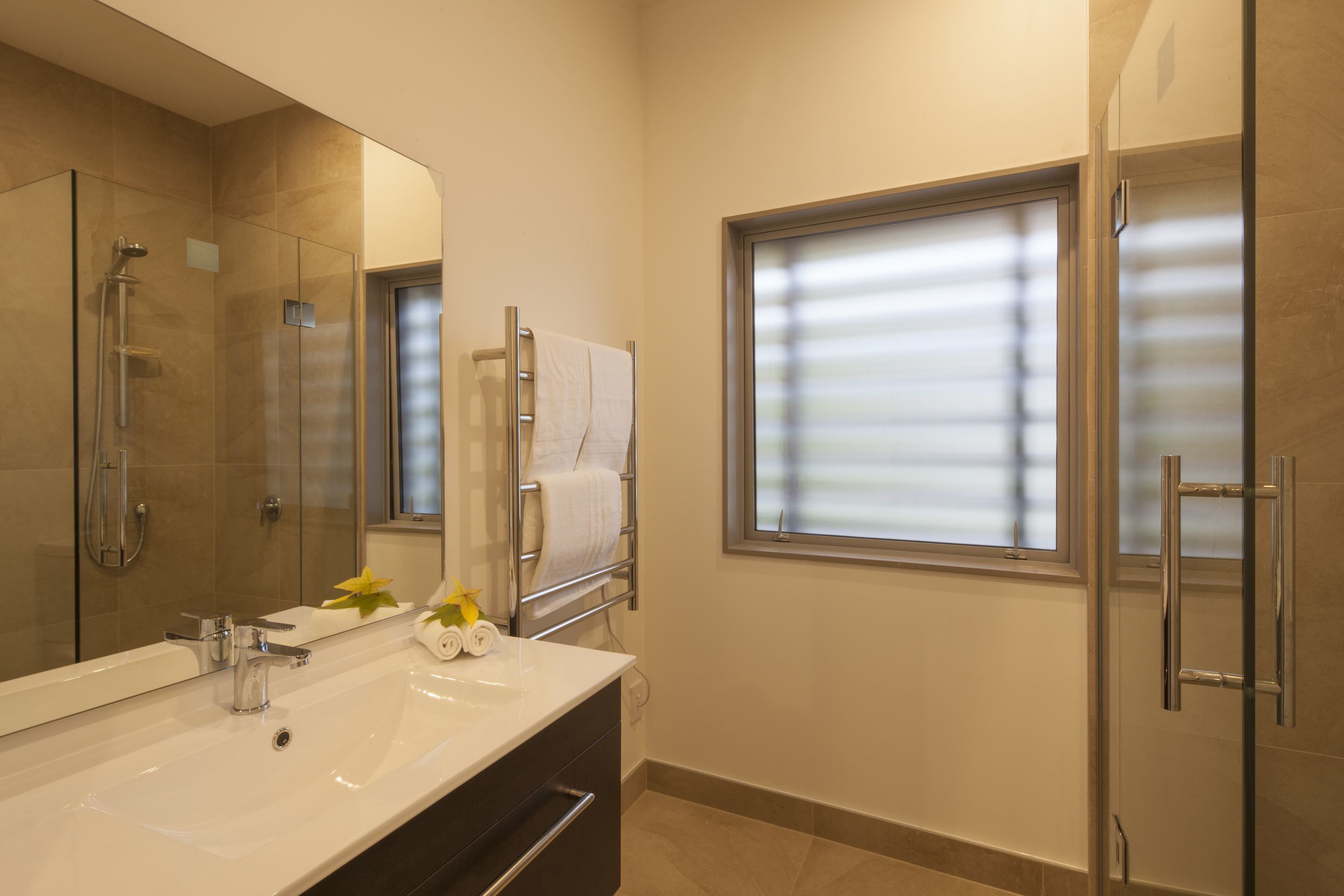 A modern bathroom with a large mirror, a sink, and a shower.
