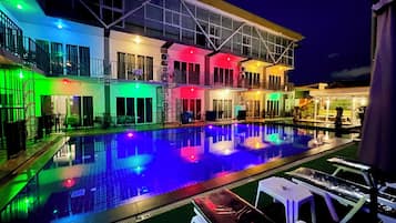 A multi-story hotel with a swimming pool, outdoor seating, and balconies.