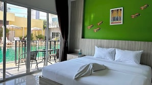 A hotel room with a large bed, a green accent wall, a balcony with a pool, and a view of the outside. - Anantra Resort Pattaya (Pattaya)