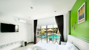 A hotel room with a bed, a flat-screen TV, a window with curtains, and a view of an outdoor pool area. - Anantra Resort Pattaya (Pattaya)