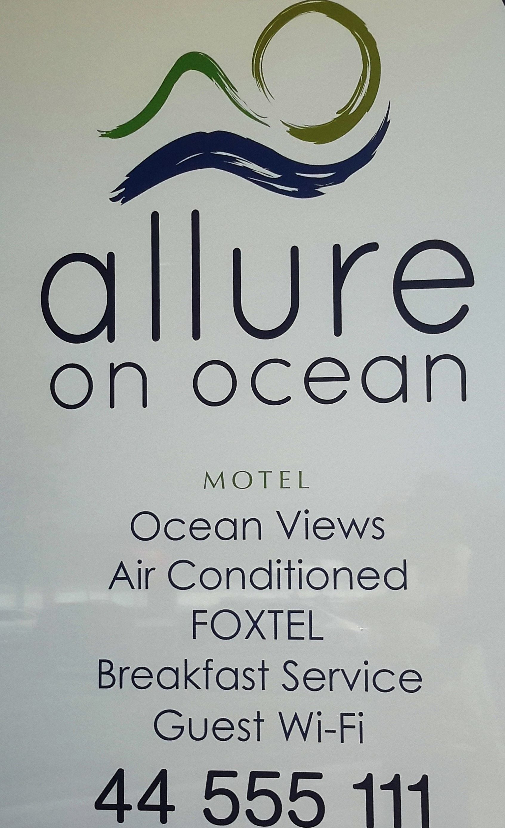A sign for 'Allure on Ocean' motel, listing features like ocean views, air conditioning, FOXTEL, breakfast service, and guest Wi-Fi.