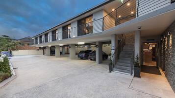 Un immeuble à plusieurs étages doté d’un parking couvert, d’un escalier et d’une caméra de surveillance.