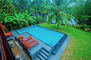 Una piscina al aire libre, sombrillas, sillones reclinables de piscina