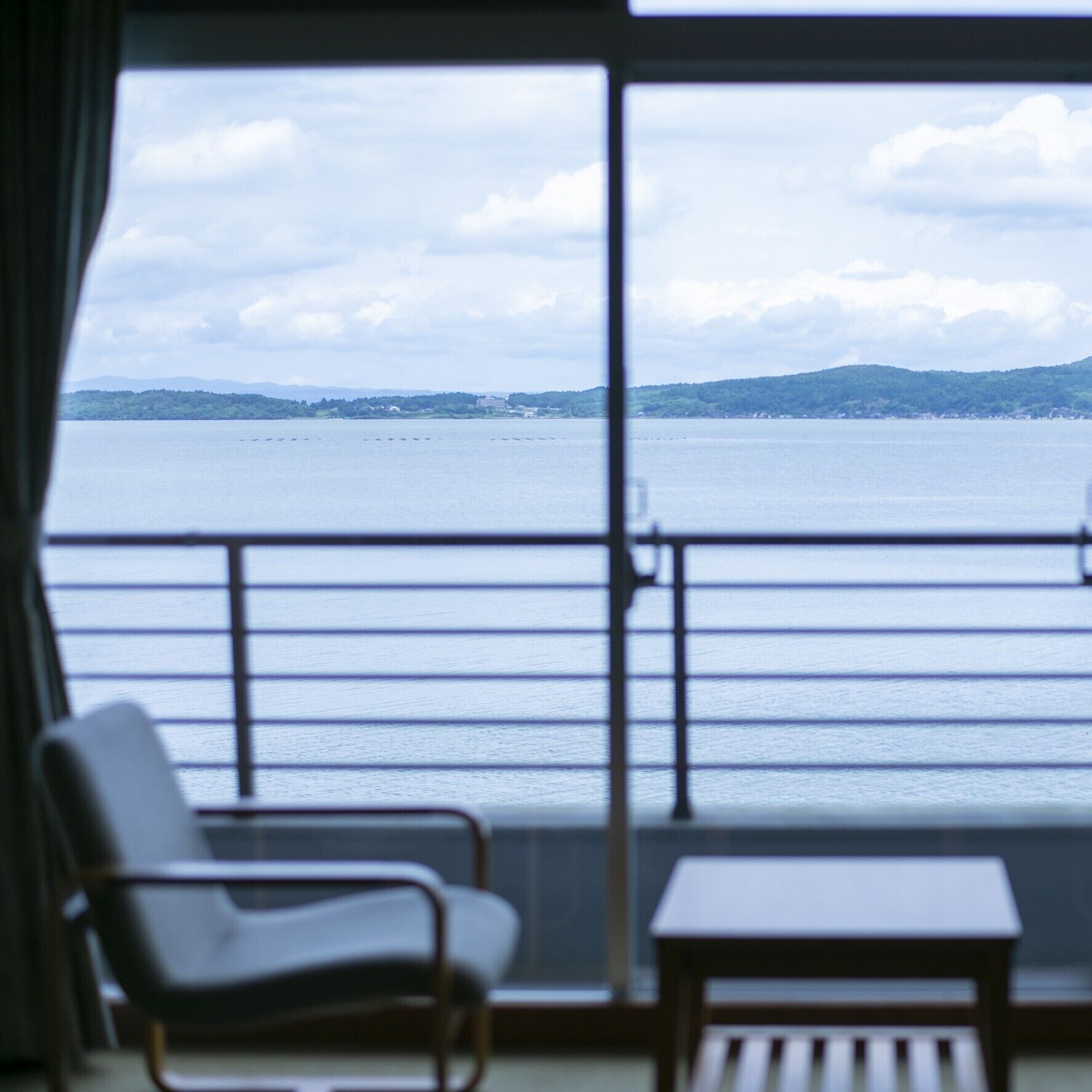 A balcony with a view of a calm body of water and distant land.
