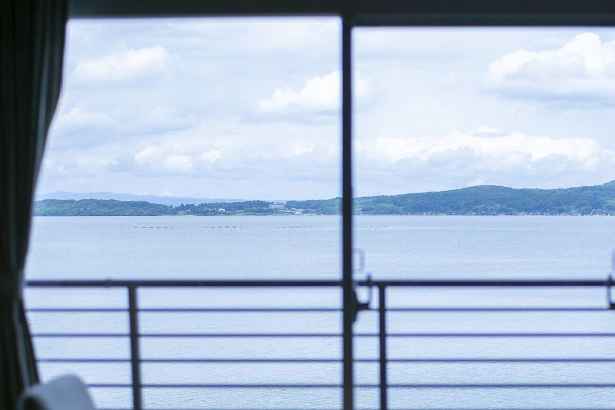 A balcony with a view of a calm body of water and distant land.