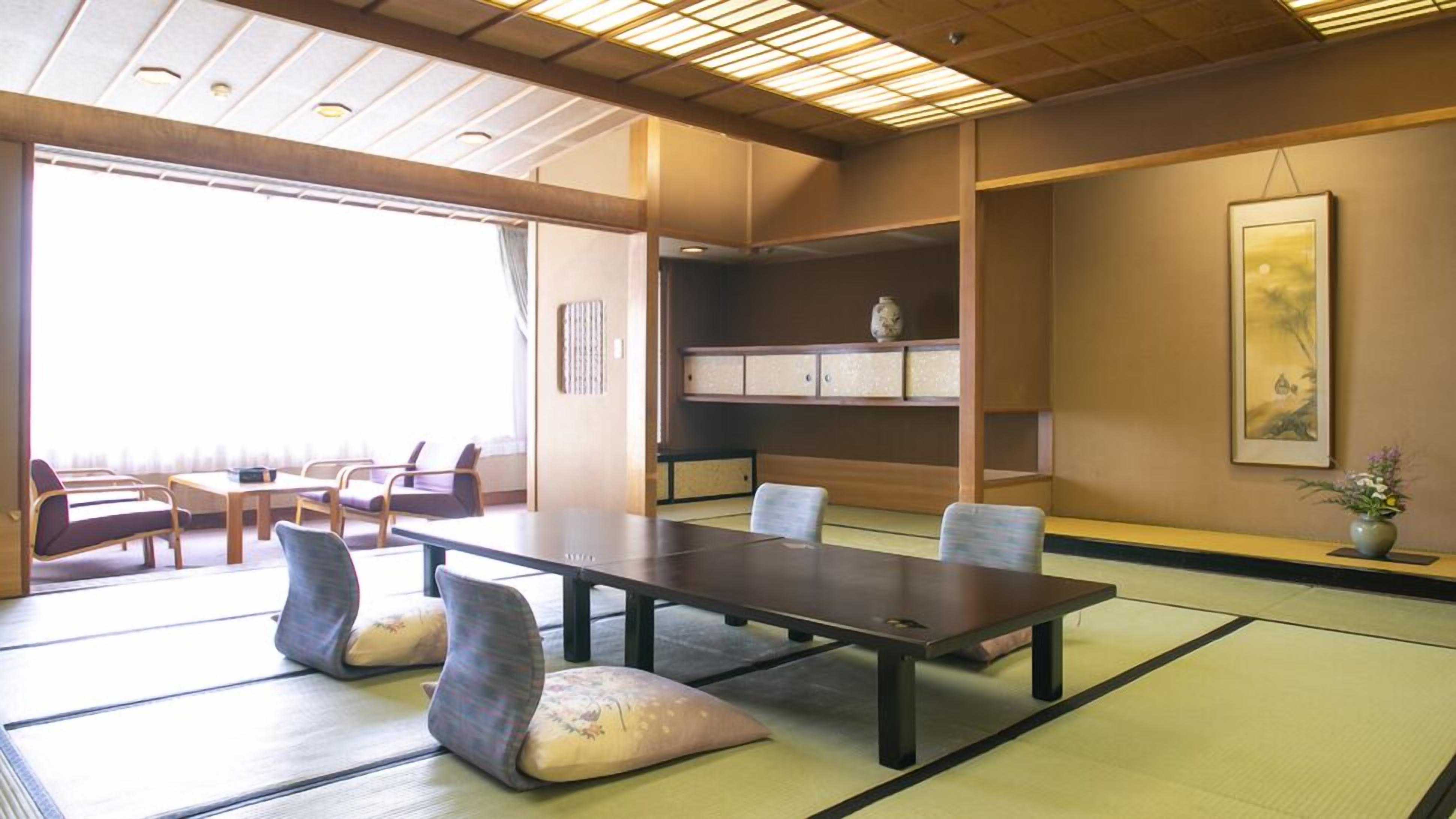 A traditional tatami mat room with a low table, chairs, and a shelf with decorative items.