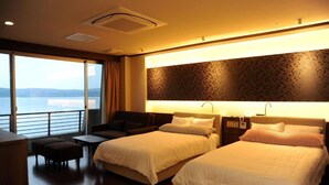 Une chambre d’hôtel avec deux lits, un canapé, une petite table et une vue sur la mer.