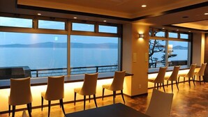 Un espace repas doté de grandes fenêtres offrant une vue sur la mer et les montagnes.