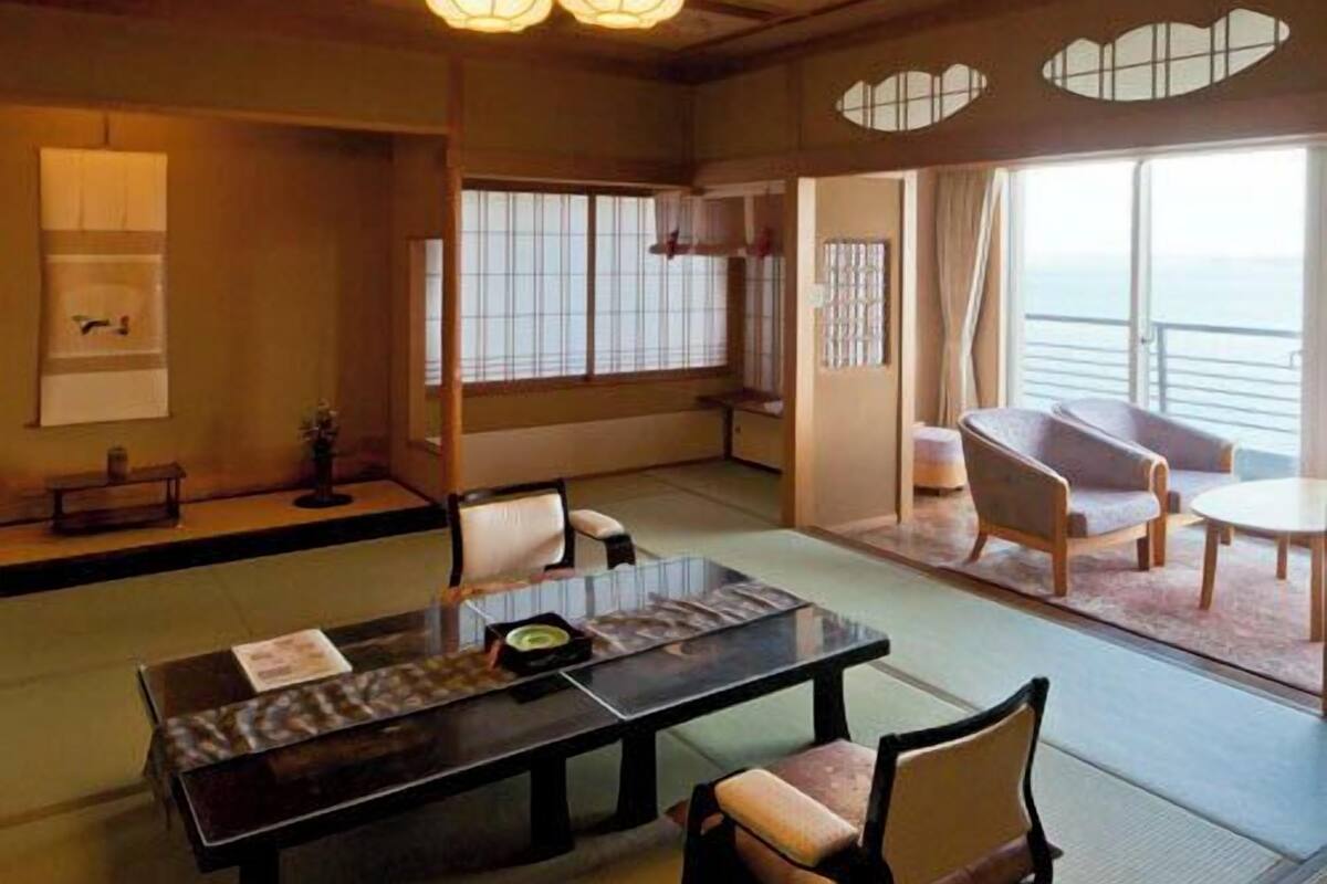 Une pièce de style japonais traditionnel, avec un sol recouvert de tatamis, une table basse avec des coussins et des portes coulissantes.