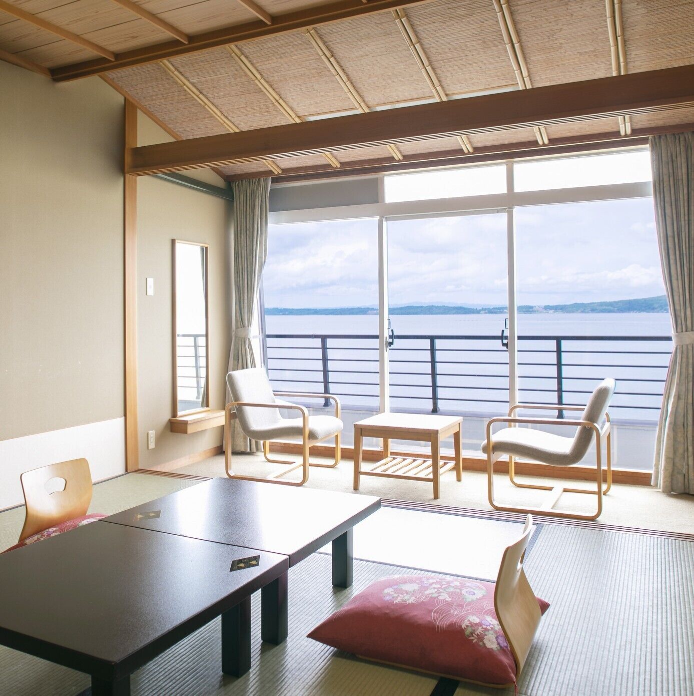 A room with a large window, a table, two chairs, and a sofa.