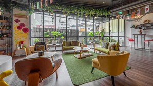 A modern interior with a green carpet, wooden furniture, and large windows overlooking a cityscape. - Light Hostel (Tainan)