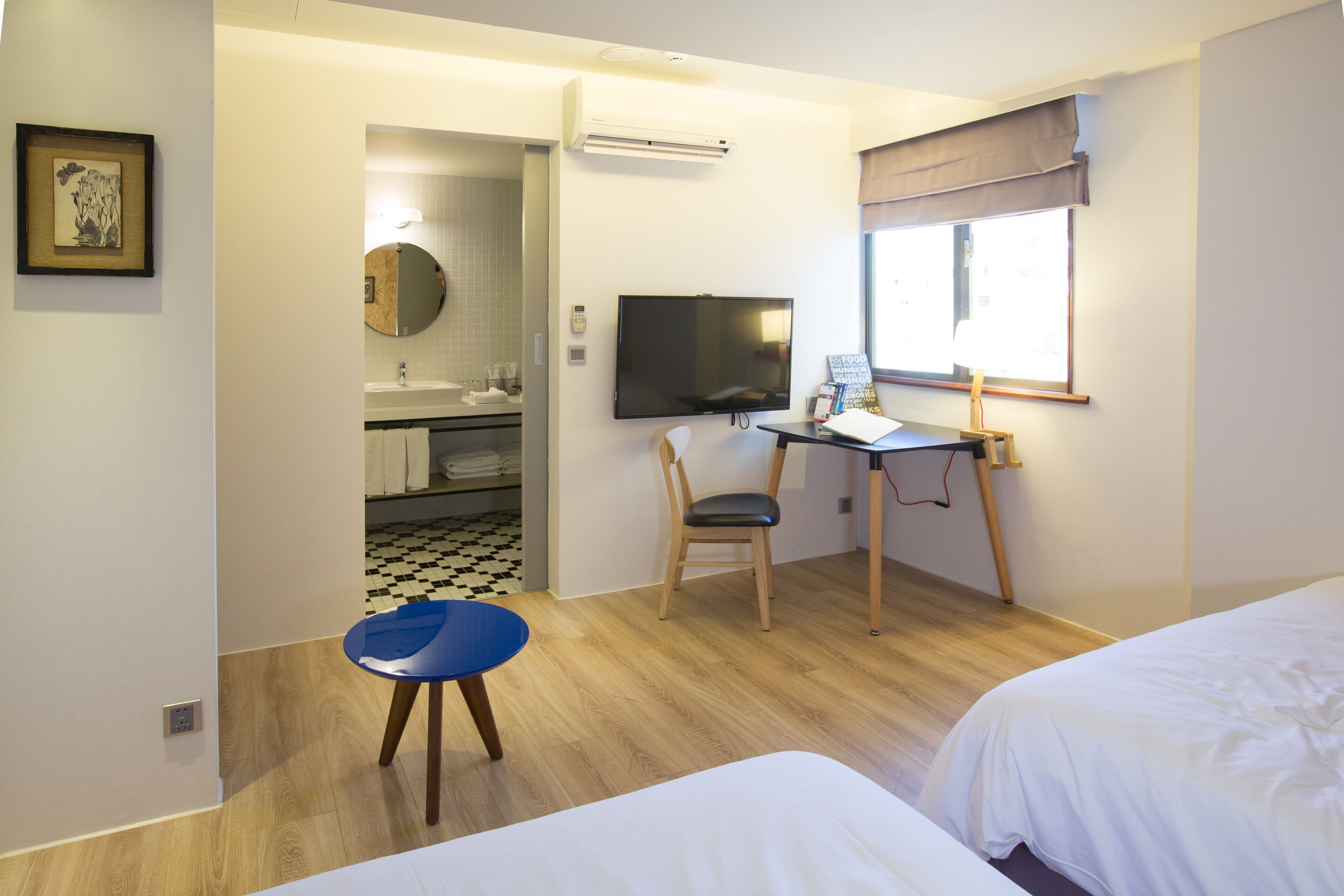 Habitación de hotel con cama, escritorio con silla, televisor y ventana con vistas.