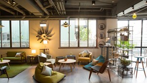 A modern interior with a green sofa, a yellow armchair, and a wooden coffee table. - Light Hostel (Tainan)