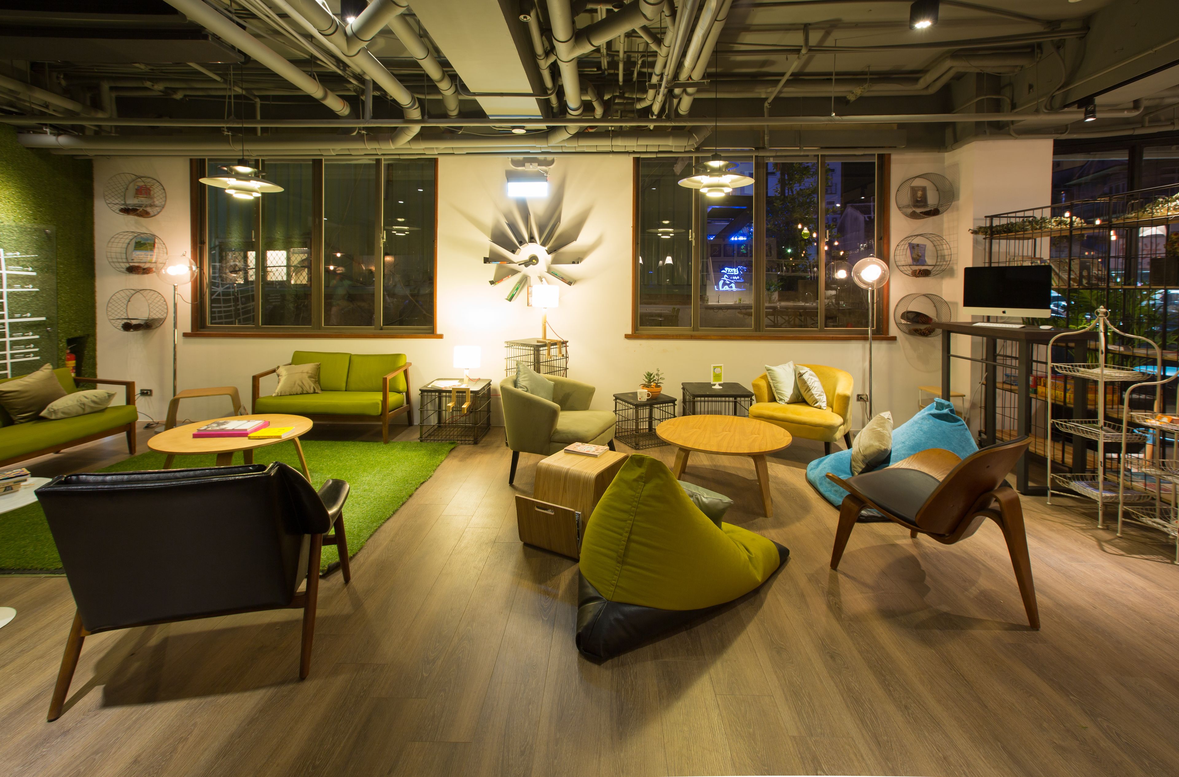 A modern lounge area with green and yellow seating, a round table, and a large window with city views.