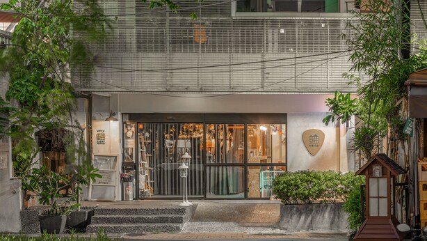 A building with a modern entrance, steps leading up to the door, and a small garden area with plants. - Light Hostel (Tainan)