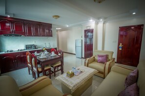 A living room with a sofa, a coffee table, and a dining area with a table and chairs.