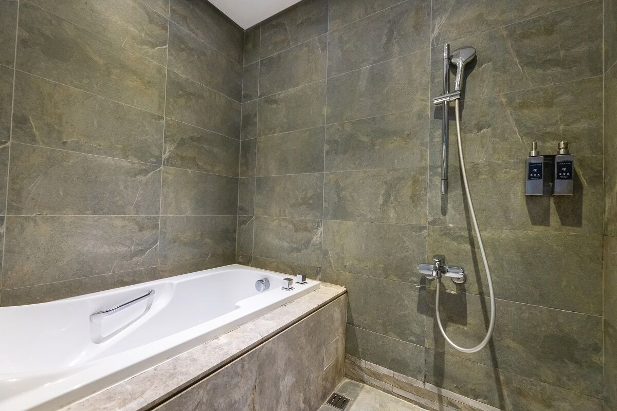 A modern bathroom with a freestanding bathtub, a handheld showerhead, and two wall-mounted water heaters.