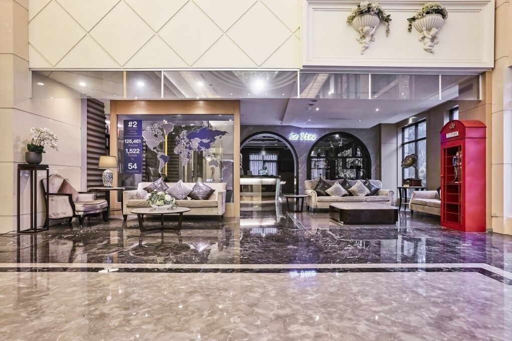 Eine geräumige Lobby mit Marmorboden, Sitzbereichen, einem Empfangstresen und einer roten Telefonzelle.