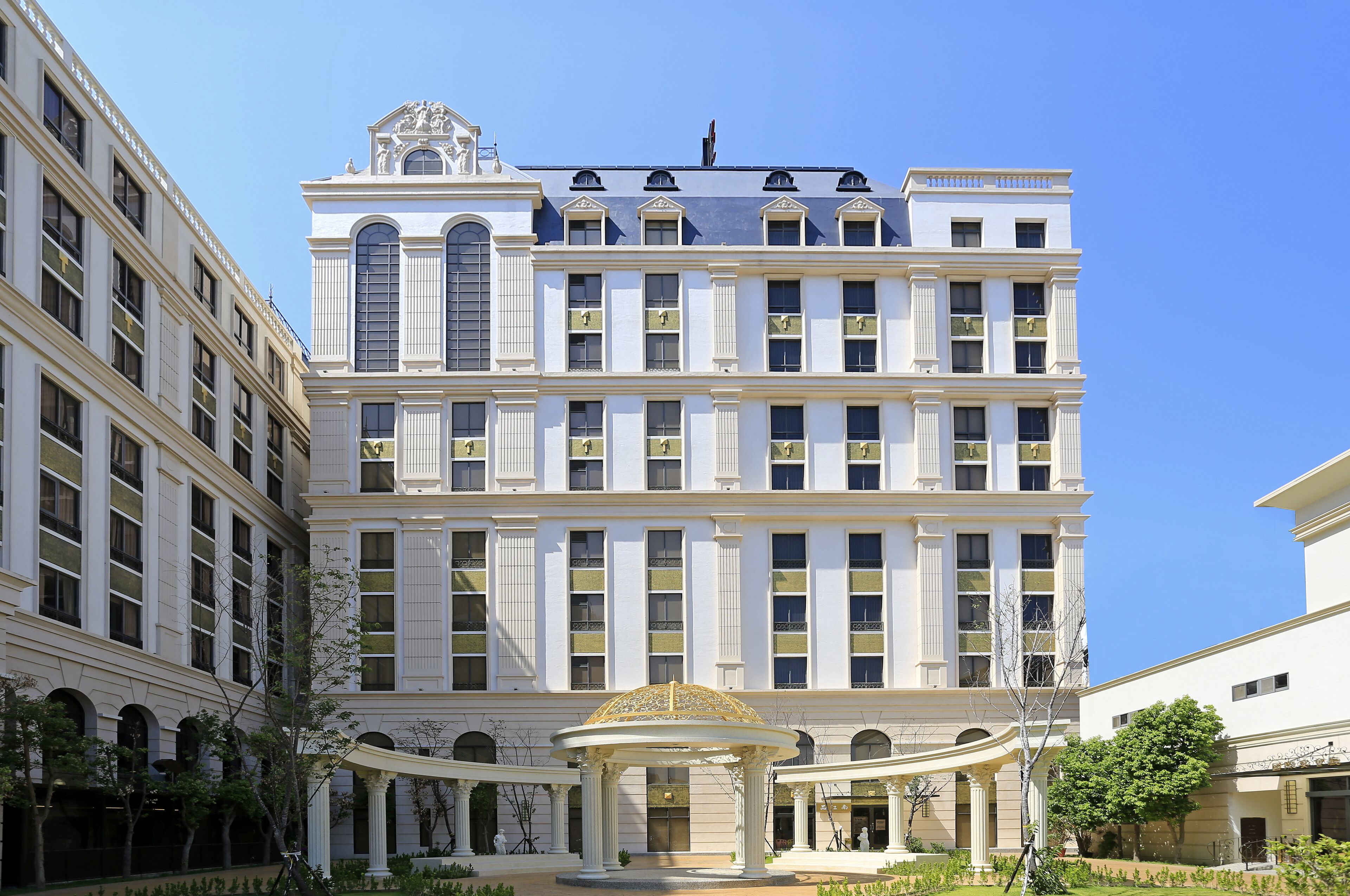 Un edificio grande de varios pisos con arquitectura clásica, que presenta un patio central con una fuente y columnas.