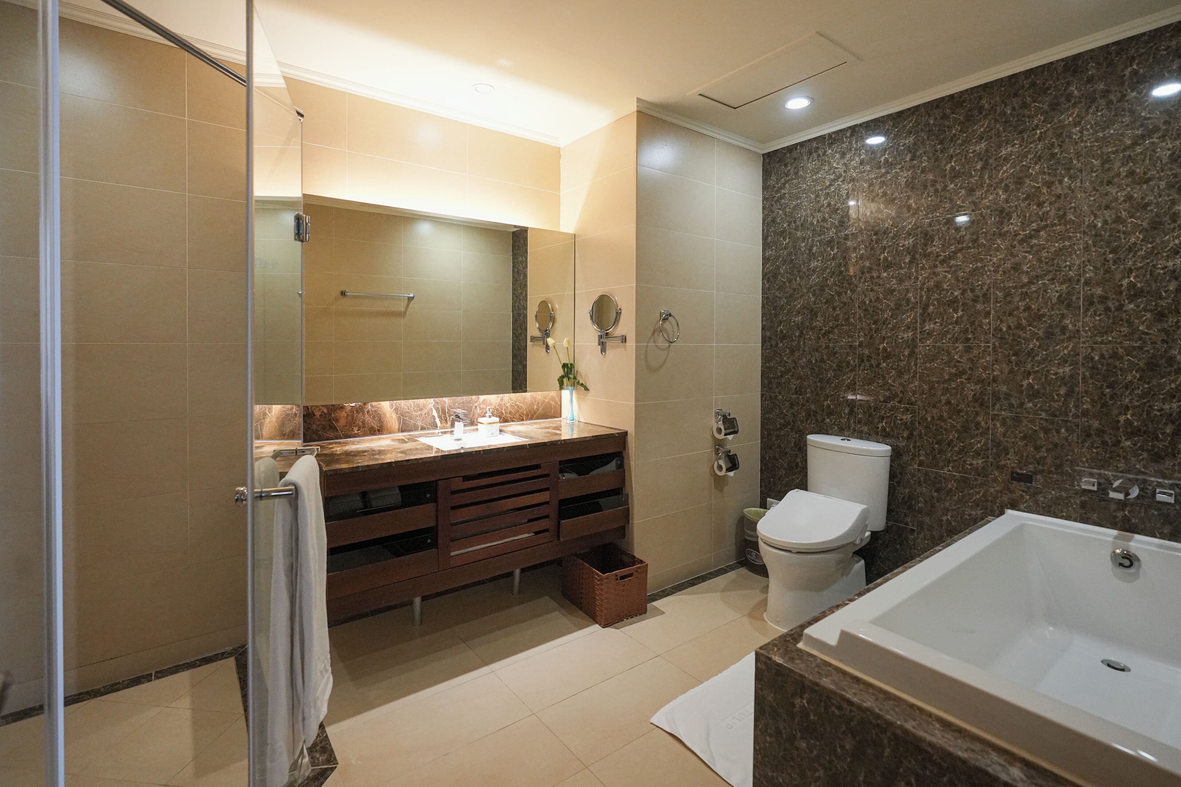 Une salle de bain moderne avec une douche à parois de verre, un meuble-lavabo avec miroir, des toilettes et une baignoire.