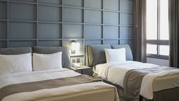 Una habitación de hotel con dos camas, una mesita de noche, una lámpara y una ventana con cortinas.