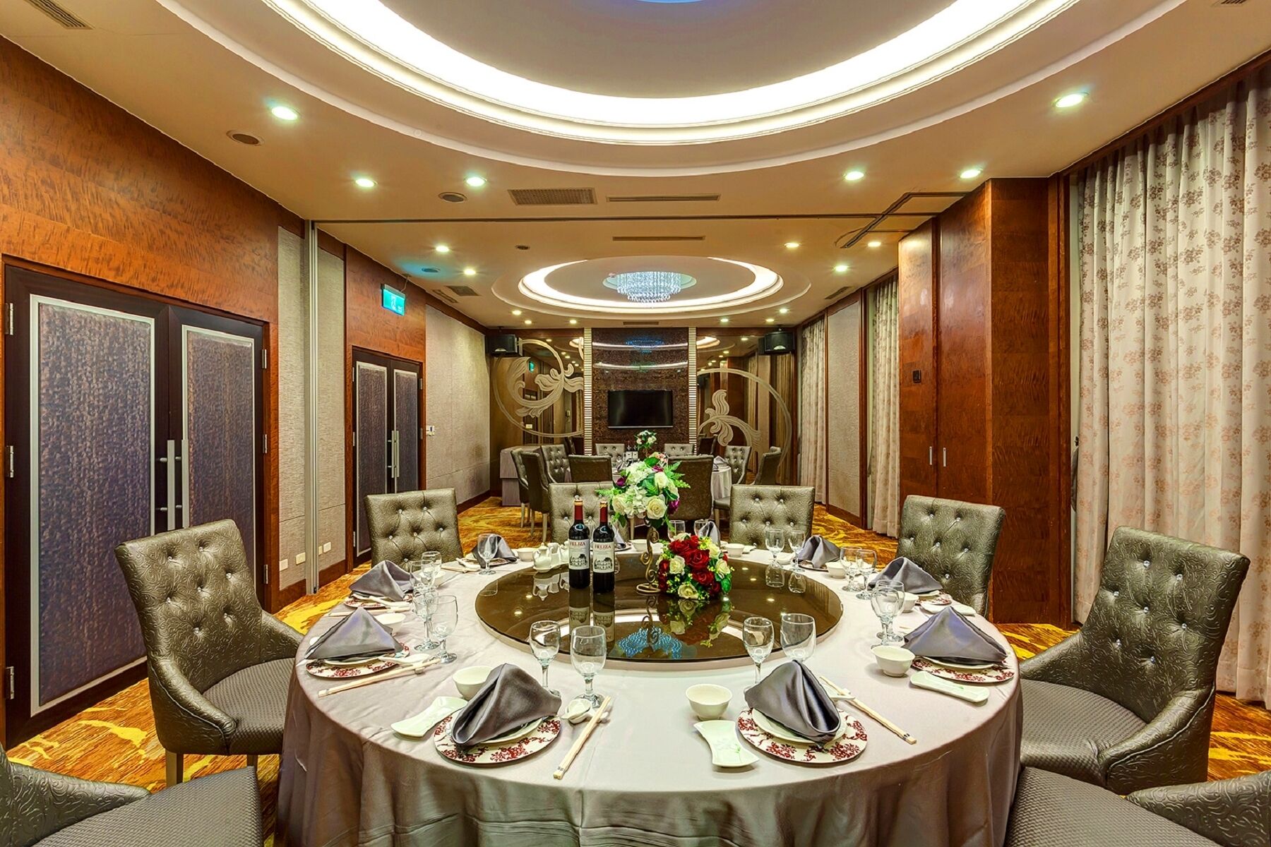 A conference room with a round table, leather chairs, and a chandelier.