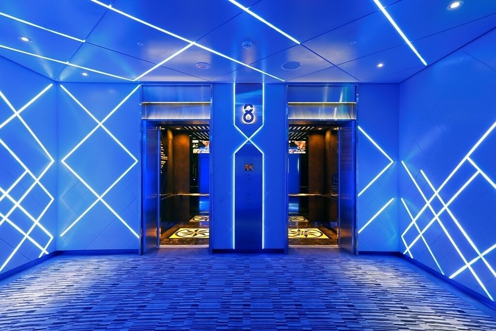 A modern elevator with geometric light patterns on the walls and floor.