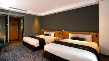 A hotel room with two beds, a patterned carpet, and a dark wall.