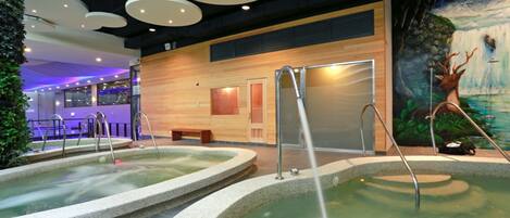 Un área de spa con dos jacuzzis, una pared de madera y un mural de una cascada.