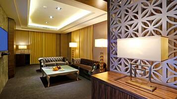 Habitación de hotel con un conjunto de sofás, una mesita de centro y un separador decorativo con patrones geométricos.