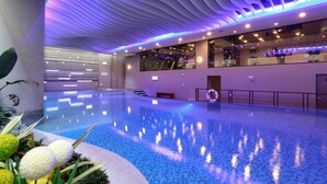 Una piscina interior moderna con techo ondulado e iluminación morada.