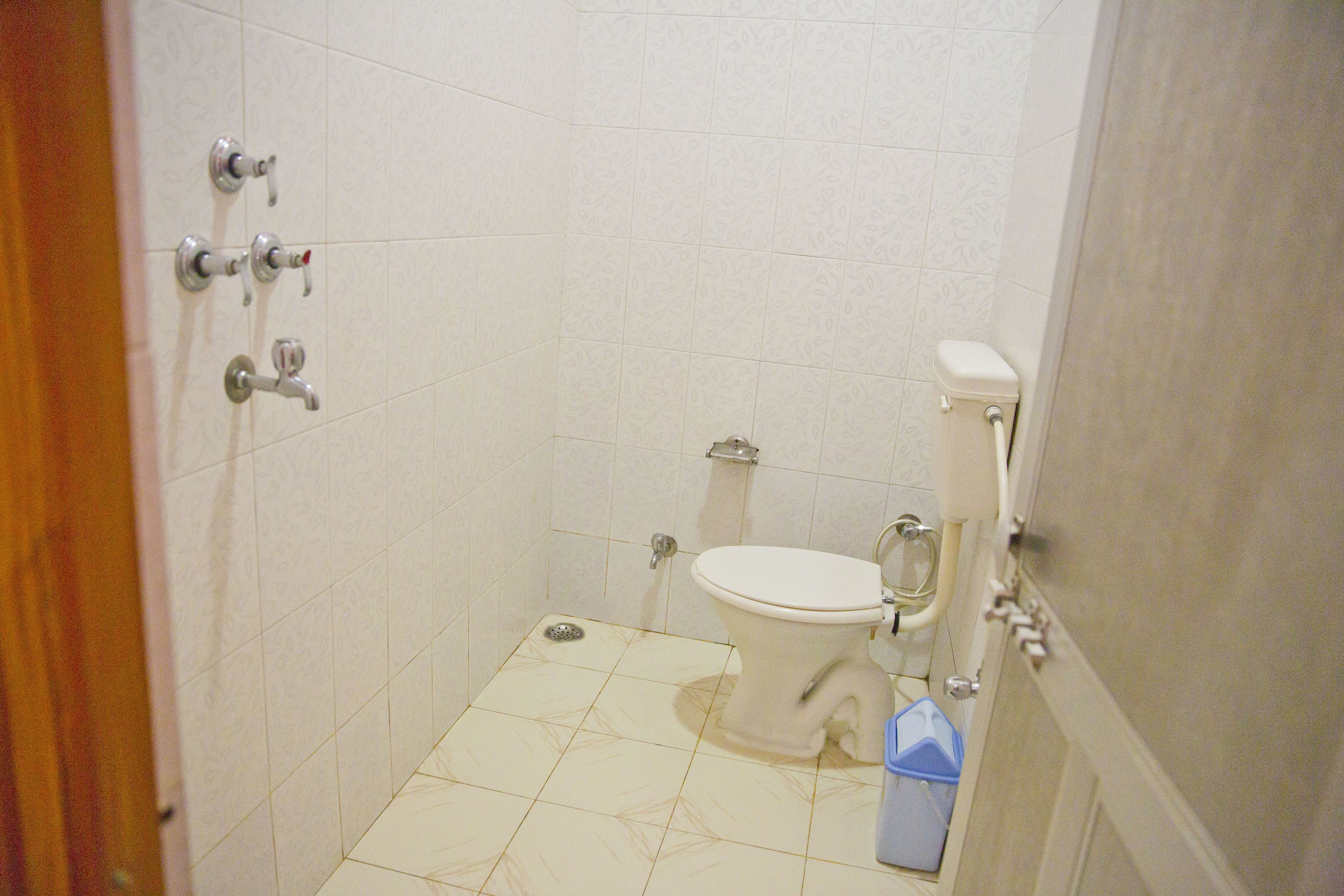A small, tiled bathroom with a toilet, a bidet, and a hand dryer.