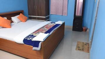 A bedroom with a wooden bed, a wardrobe, a mirror, and a blue wall.