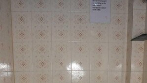 A small, basic bathroom with a toilet, a wall-mounted sink, and a tiled floor. - Shri Yoga Mandir Guest House (Varanasi)