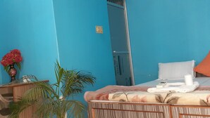 A room with a bed, a chair, a desk, a mirror, and a potted plant. - Shri Yoga Mandir Guest House (Varanasi)
