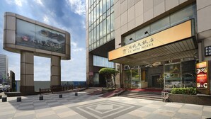 A LE MIDI HOTEL with a modern facade, large glass windows, and a prominent entrance with steps leading up to the door.