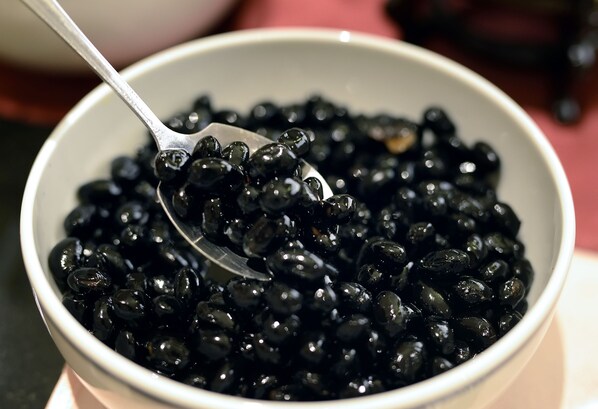 A bowl of black beans with a spoon.