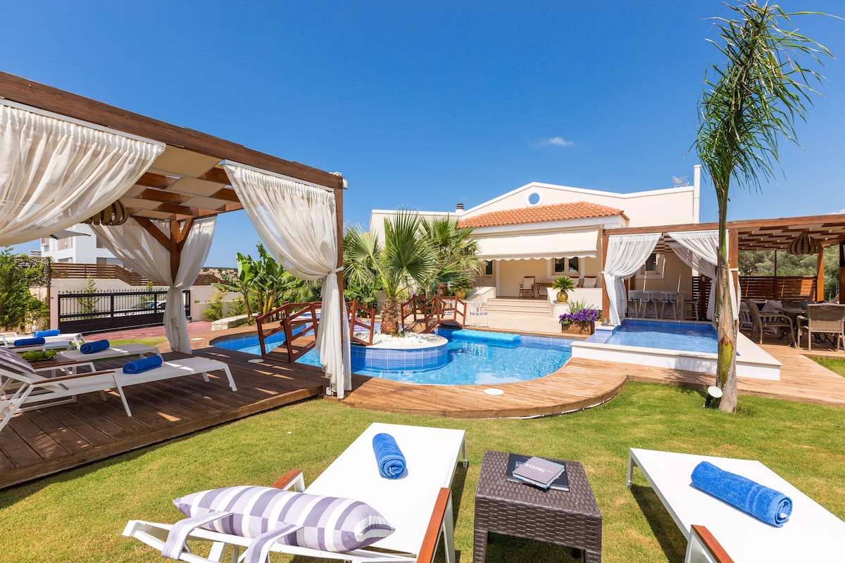 A backyard with a swimming pool, lounge chairs, and a covered patio area.