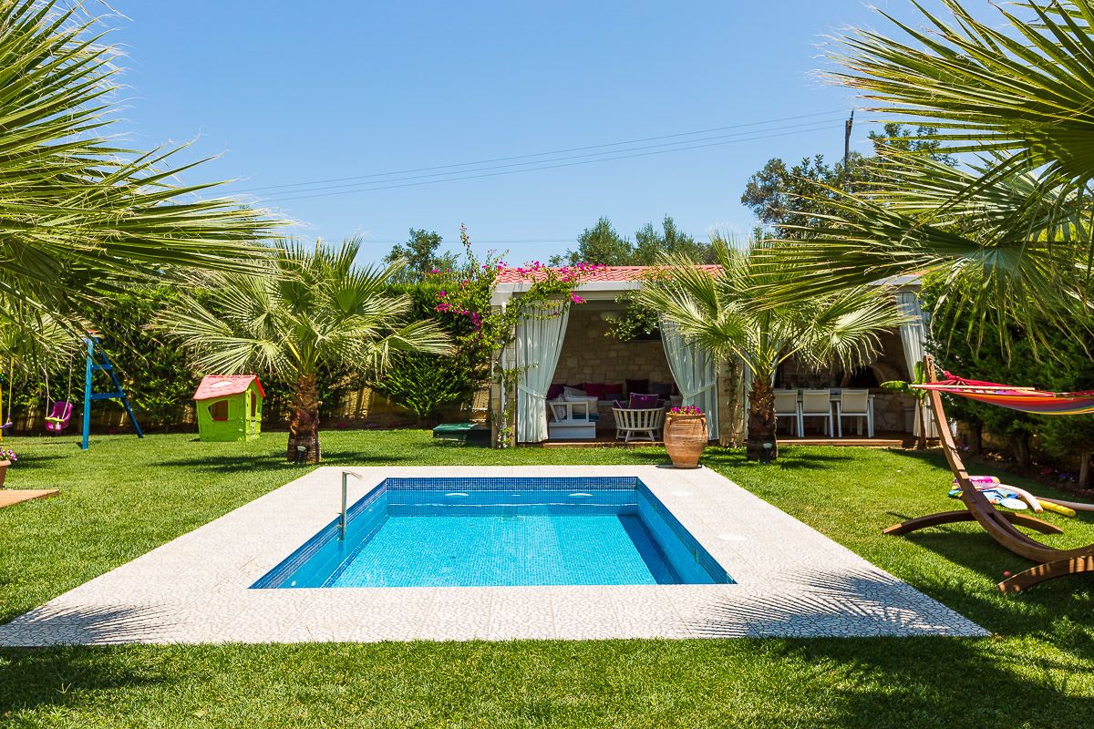 A swimming pool surrounded by palm trees and a covered patio area.