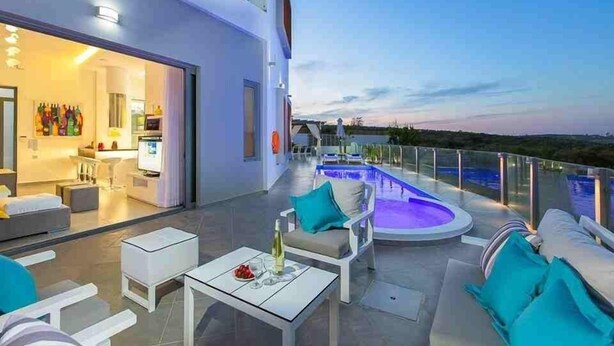 Ein moderner Außenbereich mit Pool, Sitzgelegenheiten und einer durch eine offene Tür einsehbarer Küche.