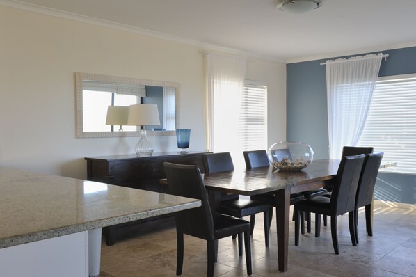 A dining area with a granite countertop, dark wooden table, and six chairs.