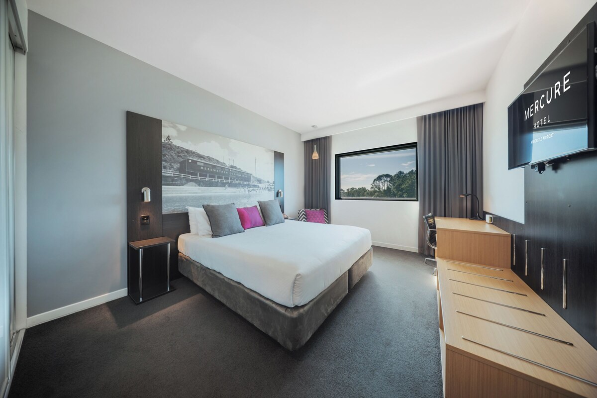 Una habitación de hotel moderna con una cama grande, un escritorio y una televisión.