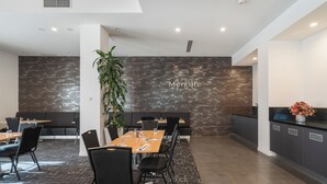 Un hall d’hôtel moderne comprenant un espace salon, un comptoir d’accueil et une grande plante.