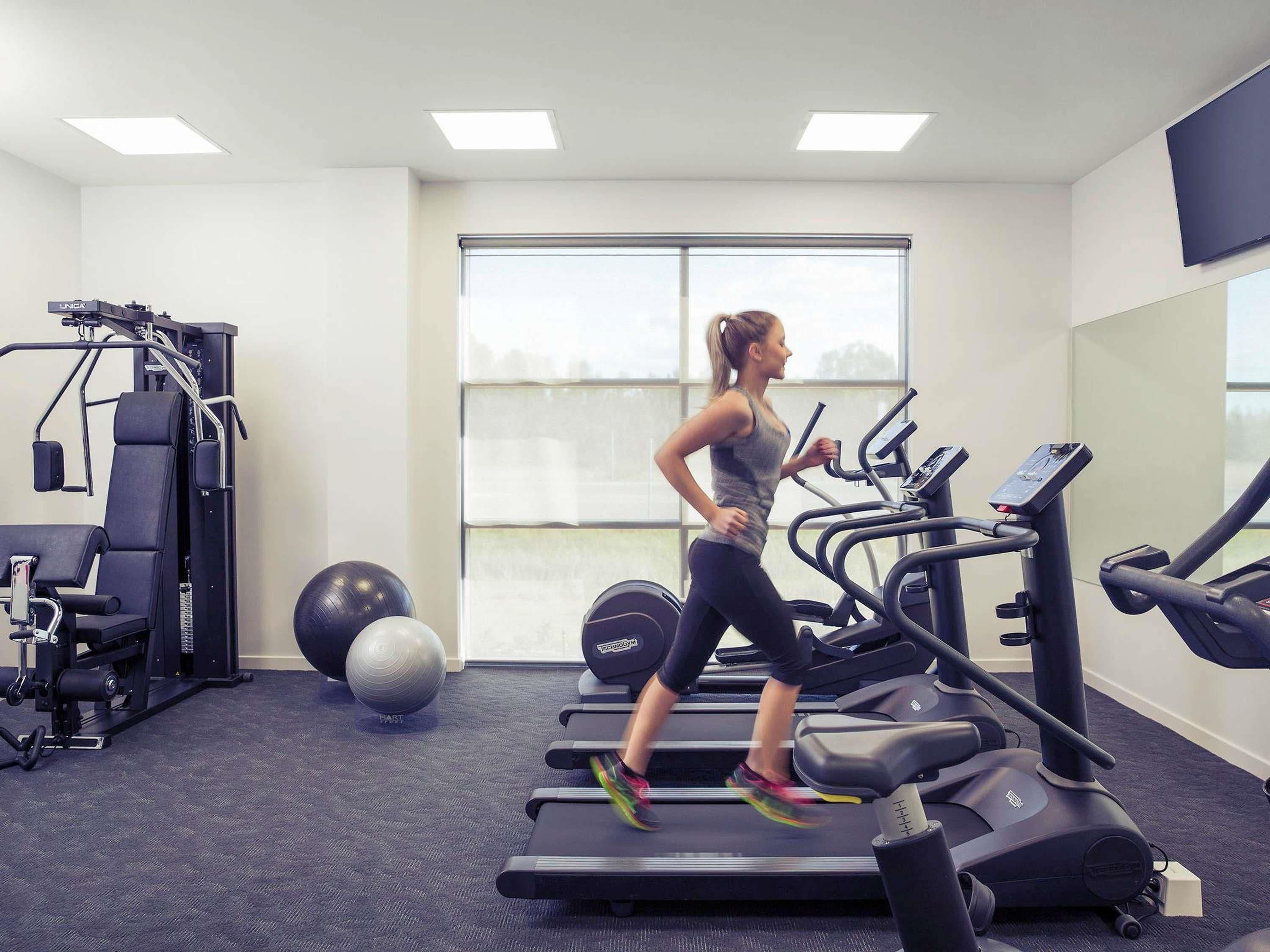 A gym with treadmills, a weight machine, and exercise balls.