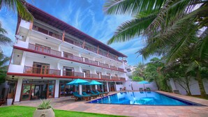 Un hotel con piscina, varios balcones y un césped bien cuidado.