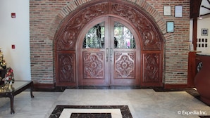 A grand entrance with a brick wall and a large wooden door with intricate carvings. - Hotel Luna Annex (Vigan)