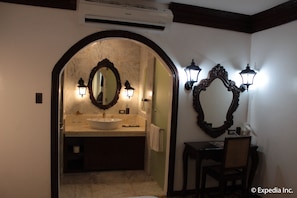 A bathroom with a marble sink, two wall-mounted mirrors, and a chair.