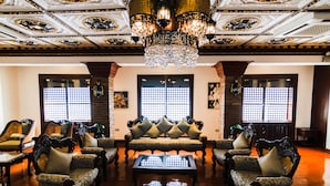 A traditional room with ornate ceiling and chandeliers, a central sofa set, and a wooden coffee table. - Hotel Luna Annex (Vigan)