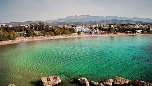 Une ville côtière dotée d’eaux turquoise cristallines, d’une plage de sable fin et bordée de montagnes.