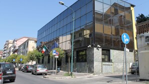 A modern building with a glass facade, parked cars, and a clear sky. - Hotel Cristal Eboli (Eboli)